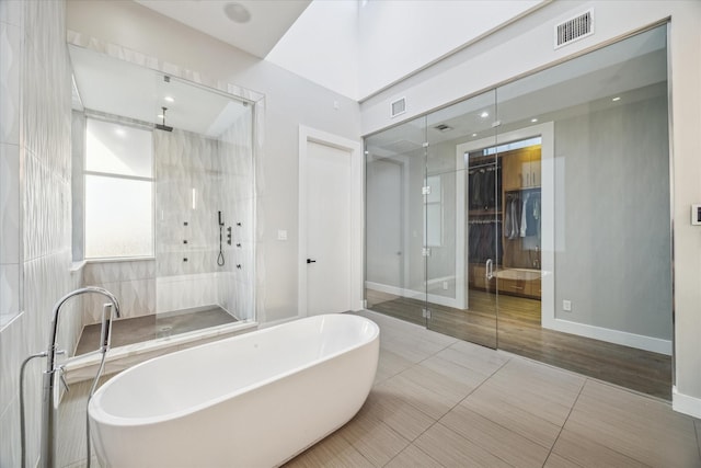 bathroom with a stall shower, a freestanding tub, visible vents, and baseboards