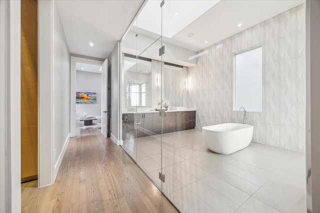 full bathroom with a freestanding tub, vanity, and wood finished floors