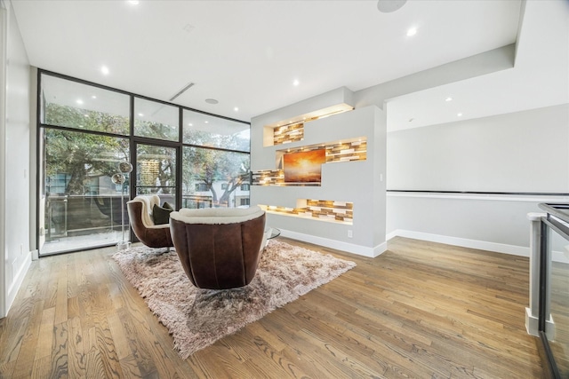 interior space with expansive windows, recessed lighting, baseboards, and wood finished floors