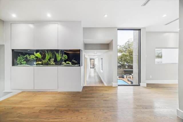 unfurnished living room featuring expansive windows, baseboards, wood finished floors, and recessed lighting