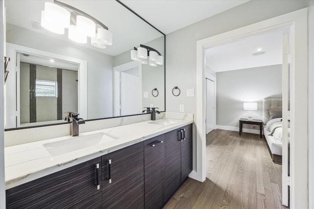 bathroom with wood finished floors, double vanity, a sink, and ensuite bathroom