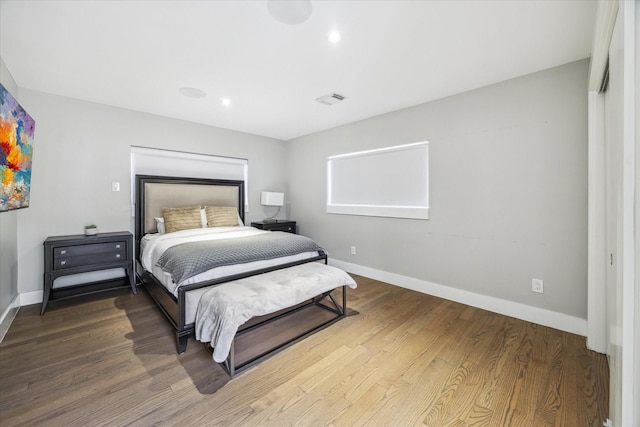 bedroom with visible vents, baseboards, and wood finished floors