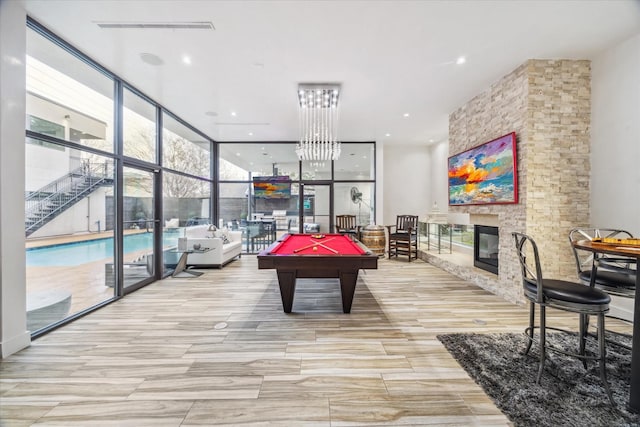 recreation room with billiards, visible vents, a stone fireplace, floor to ceiling windows, and recessed lighting