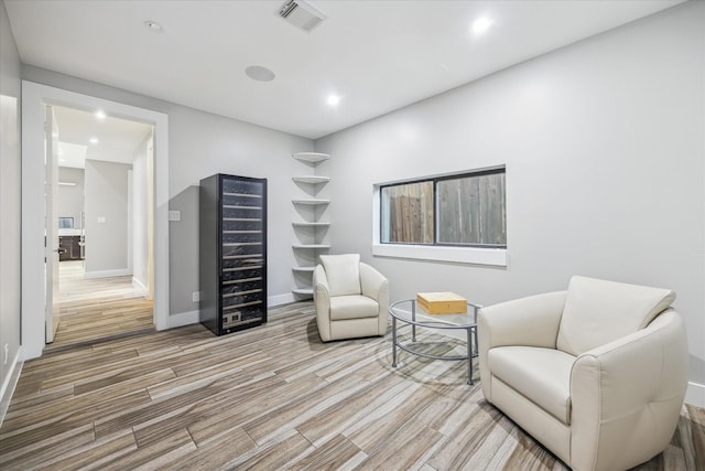 sitting room with recessed lighting, visible vents, wood finished floors, beverage cooler, and baseboards