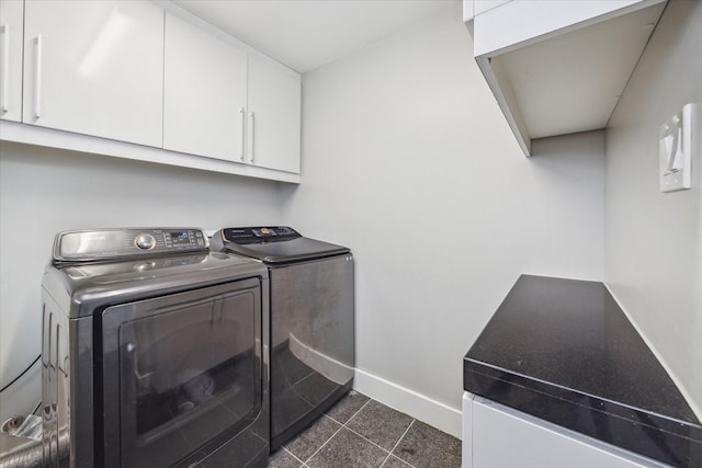 laundry area with cabinet space, dark tile patterned floors, baseboards, and washer and clothes dryer