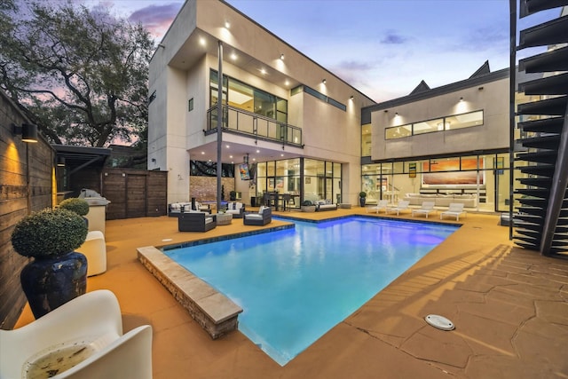 pool at dusk featuring an outdoor pool, outdoor lounge area, and a patio