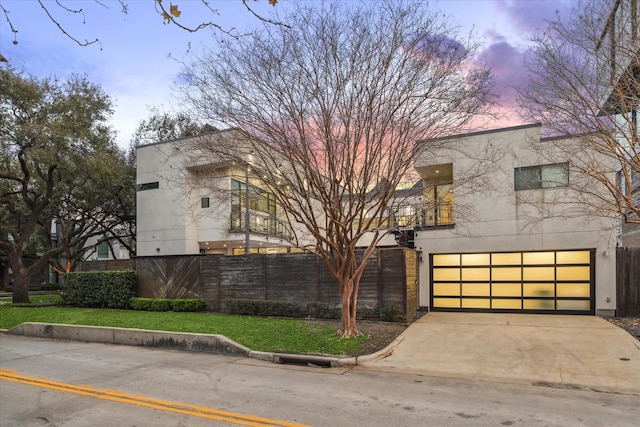 view of front of home featuring a garage, fence, driveway, and stucco siding