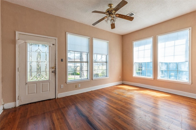 foyer entrance featuring baseboards, wood-type flooring, visible vents, and a textured ceiling