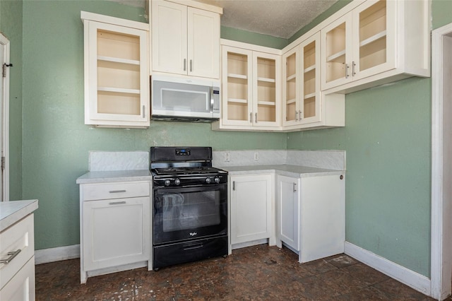 kitchen featuring black gas range, baseboards, light countertops, and glass insert cabinets