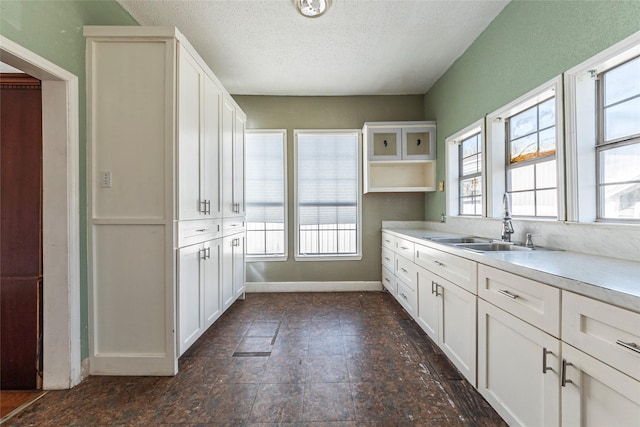 kitchen featuring light countertops, a wealth of natural light, white cabinets, and a sink