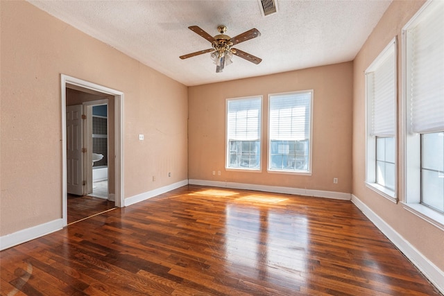 empty room with baseboards, visible vents, a textured ceiling, and hardwood / wood-style floors