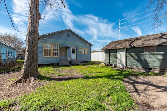 view of front of home featuring entry steps, fence, an outbuilding, and a front yard