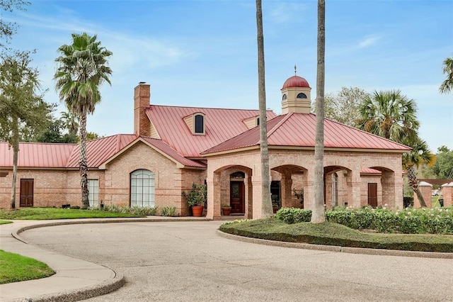 view of front of house with a standing seam roof, metal roof, brick siding, and a chimney