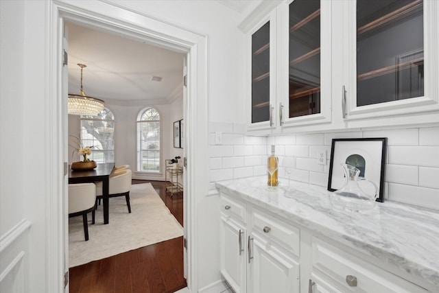 bar featuring dark wood finished floors, tasteful backsplash, crown molding, and decorative light fixtures