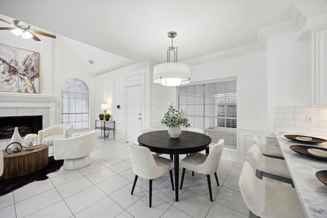 dining room with light tile patterned floors, vaulted ceiling, crown molding, and a decorative wall