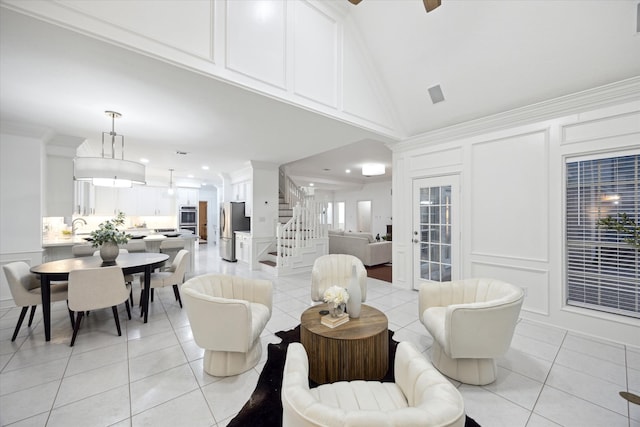 living room with high vaulted ceiling, a decorative wall, light tile patterned floors, ceiling fan, and stairs