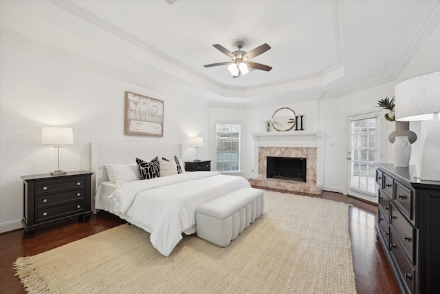 bedroom featuring a raised ceiling, multiple windows, access to exterior, and dark wood-type flooring