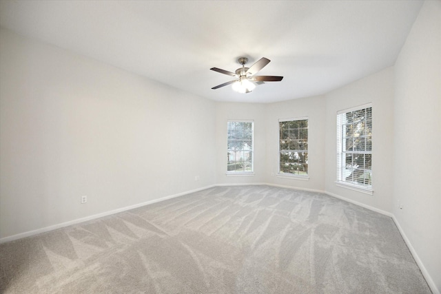 carpeted spare room with baseboards, a healthy amount of sunlight, and a ceiling fan