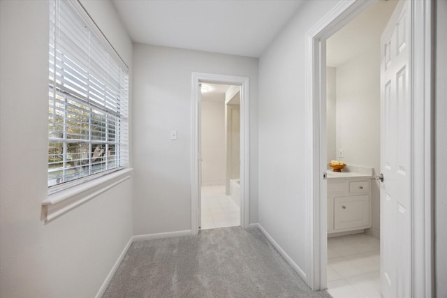 hall featuring light colored carpet and baseboards