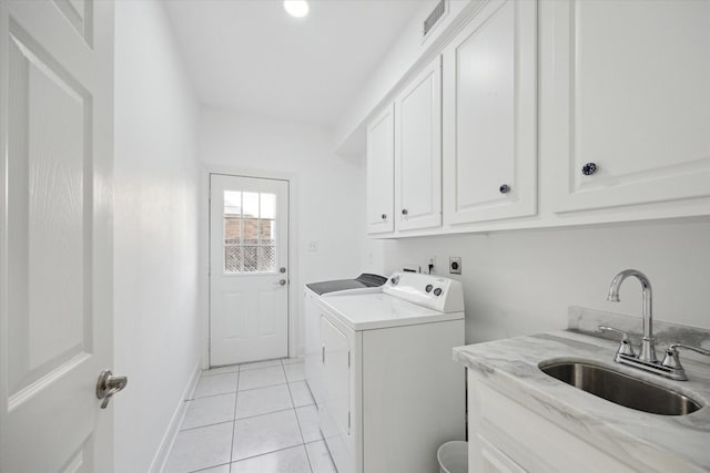 clothes washing area featuring light tile patterned floors, baseboards, separate washer and dryer, cabinet space, and a sink