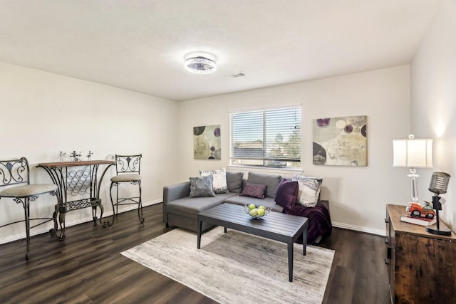 living area with baseboards, visible vents, and wood finished floors