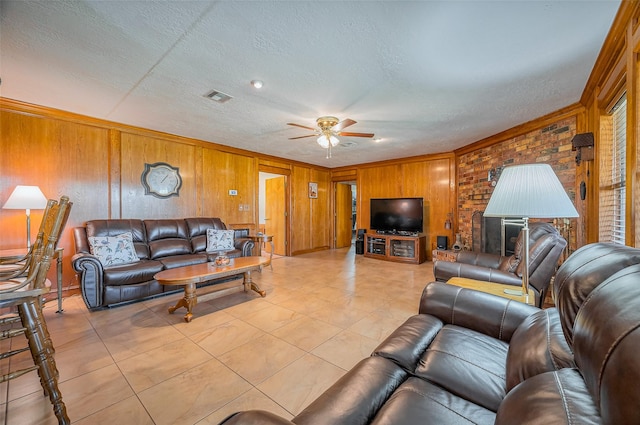 living area with visible vents, a ceiling fan, a textured ceiling, crown molding, and light tile patterned floors