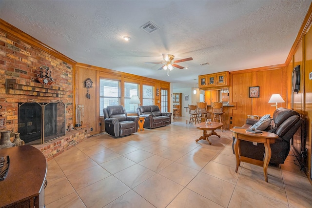 living room featuring visible vents, a brick fireplace, wood walls, light tile patterned floors, and a textured ceiling