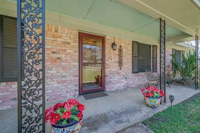 property entrance featuring a porch and brick siding