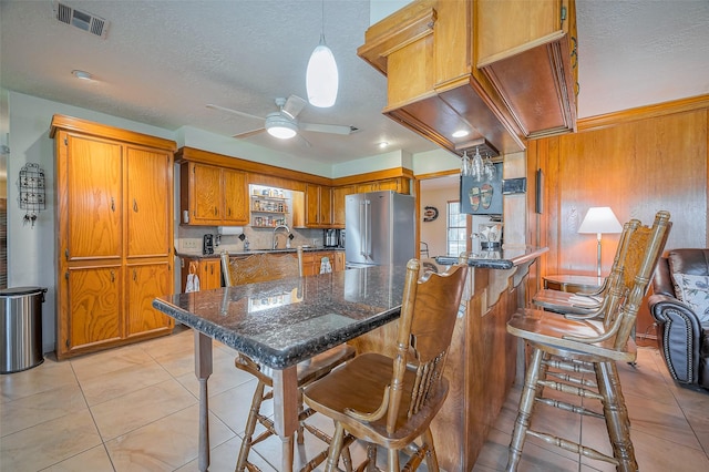 kitchen featuring visible vents, brown cabinets, light tile patterned floors, ceiling fan, and high end refrigerator