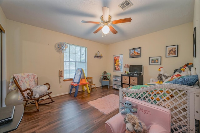 bedroom with dark wood-style floors, visible vents, a ceiling fan, and baseboards