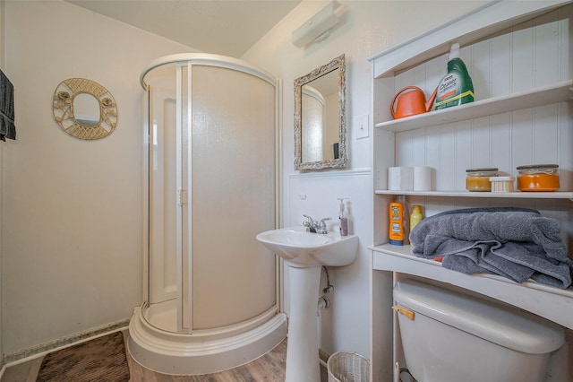 full bath featuring a sink, toilet, wood finished floors, and a shower stall