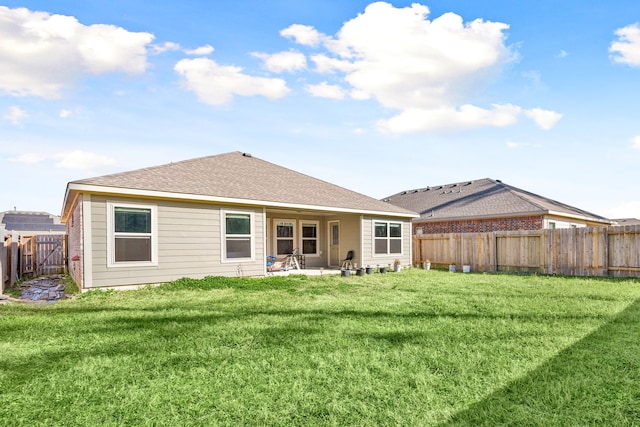 rear view of house featuring a shingled roof, a patio area, a fenced backyard, and a lawn