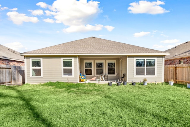 rear view of property featuring a fenced backyard, a yard, and roof with shingles