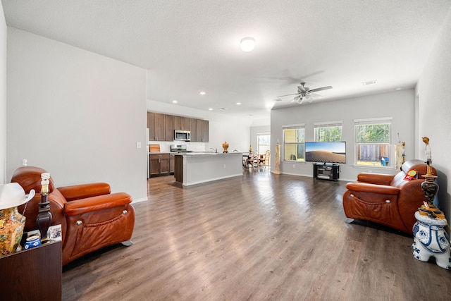 living area with recessed lighting, ceiling fan, a textured ceiling, and wood finished floors