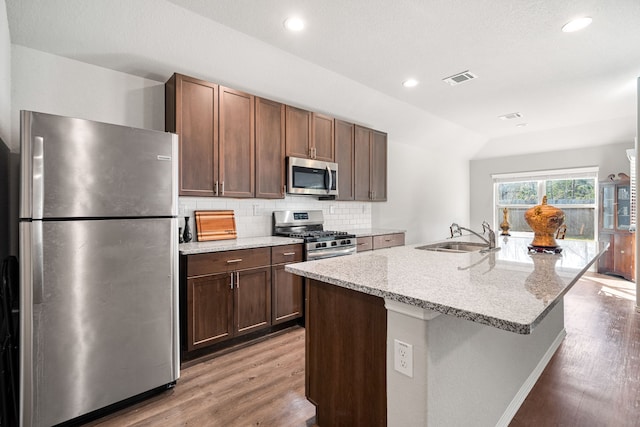 kitchen featuring wood finished floors, a sink, visible vents, appliances with stainless steel finishes, and decorative backsplash