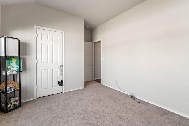 unfurnished bedroom featuring carpet floors, baseboards, and vaulted ceiling