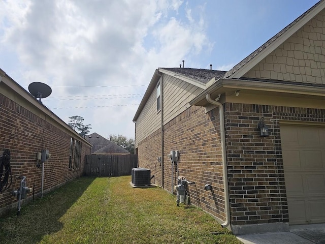 view of side of home featuring cooling unit, a lawn, a garage, and brick siding