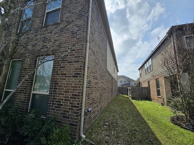 view of home's exterior featuring a yard, fence, and brick siding