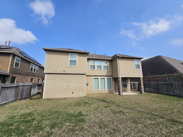 back of house with a fenced backyard, a patio area, and a yard