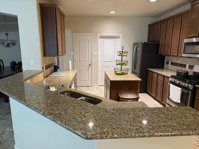 kitchen with dark stone counters, tasteful backsplash, appliances with stainless steel finishes, and a sink