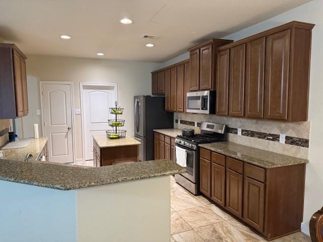 kitchen featuring decorative backsplash, stone countertops, visible vents, and appliances with stainless steel finishes