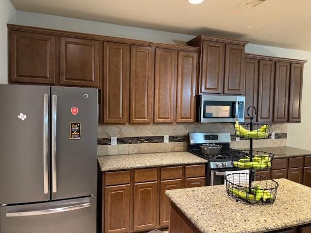 kitchen featuring a center island, light stone counters, tasteful backsplash, and stainless steel appliances