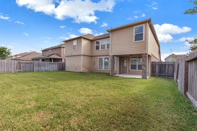 rear view of property featuring brick siding, a lawn, a fenced backyard, and a patio