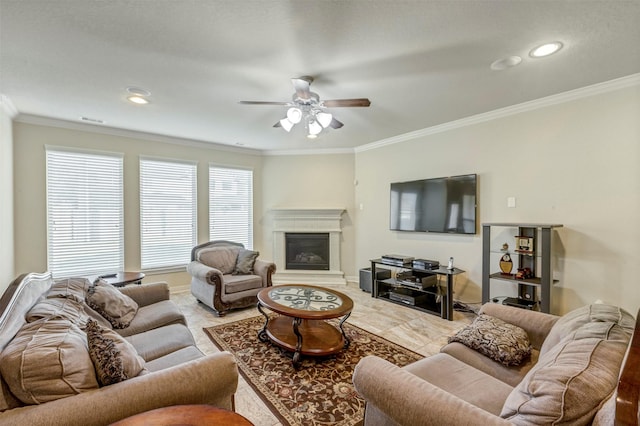living area with ceiling fan, crown molding, and a glass covered fireplace