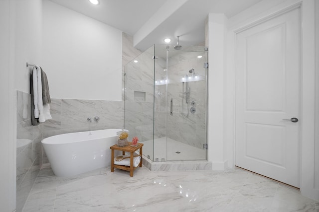 bathroom featuring marble finish floor, a freestanding tub, a marble finish shower, and recessed lighting