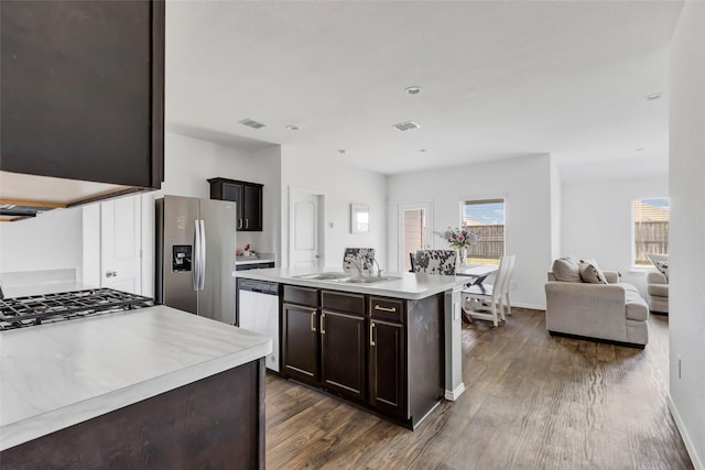 kitchen featuring dark wood finished floors, a sink, stainless steel appliances, light countertops, and dark brown cabinets