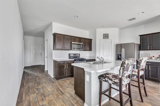 kitchen featuring visible vents, light countertops, a kitchen breakfast bar, stainless steel appliances, and a sink