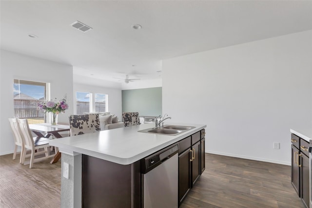 kitchen with stainless steel dishwasher, light countertops, dark wood finished floors, and a sink