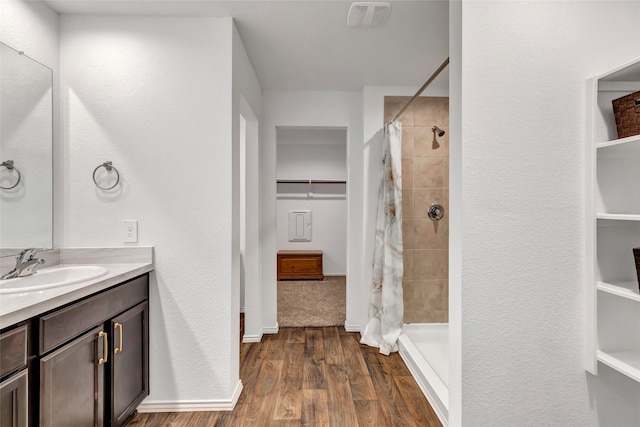 bathroom featuring a shower stall, vanity, baseboards, and wood finished floors