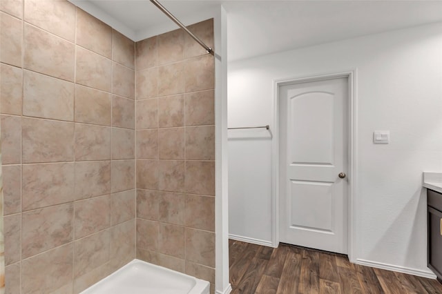 full bath with tiled shower, wood finished floors, and vanity